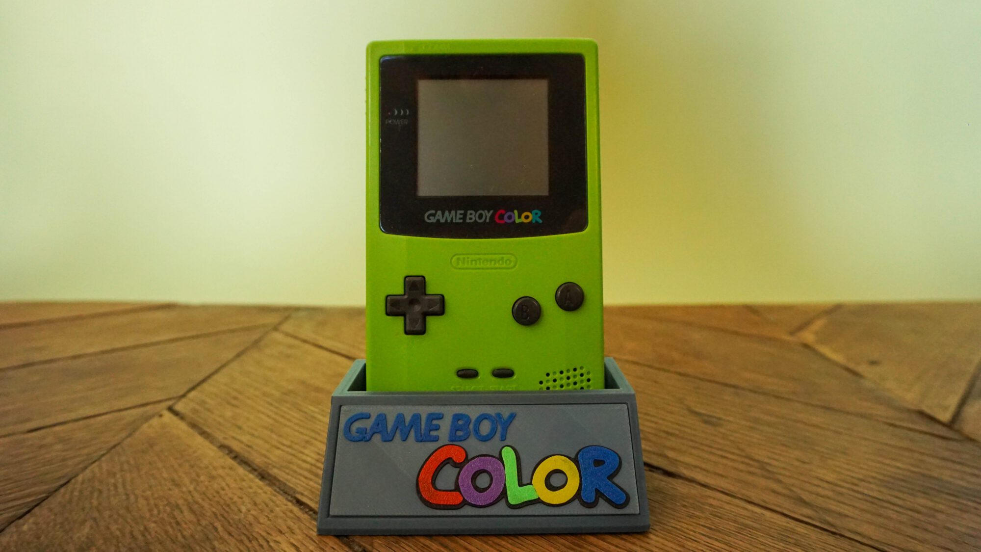Photo d'une Game Boy Color Verte Fluo sur son socle, vue de face