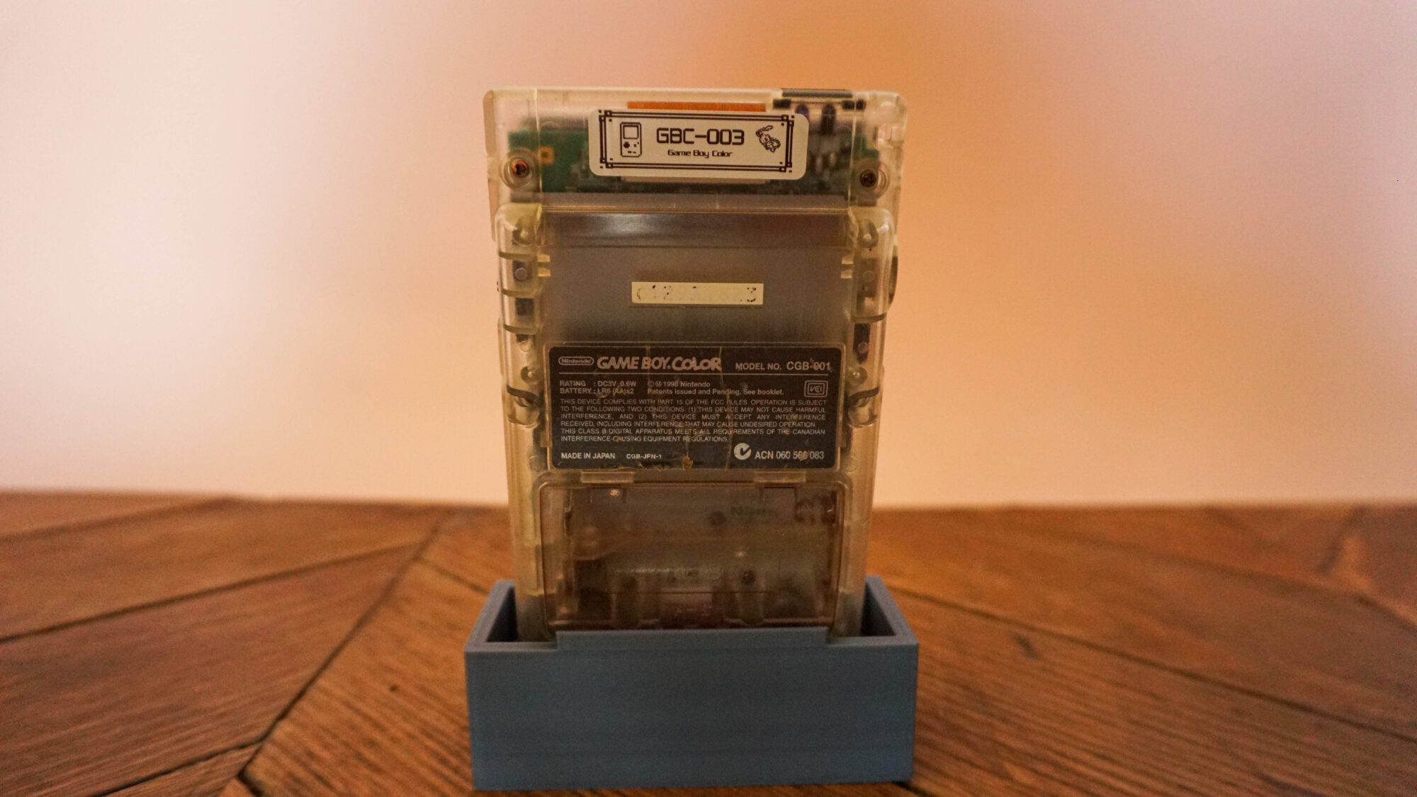 Photo d'une Game Boy Color Transparente sur son socle, vue de dos