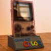 Photo d'une Game Boy Color Transparente/Violette restaurée sur son socle, vue de 3/4