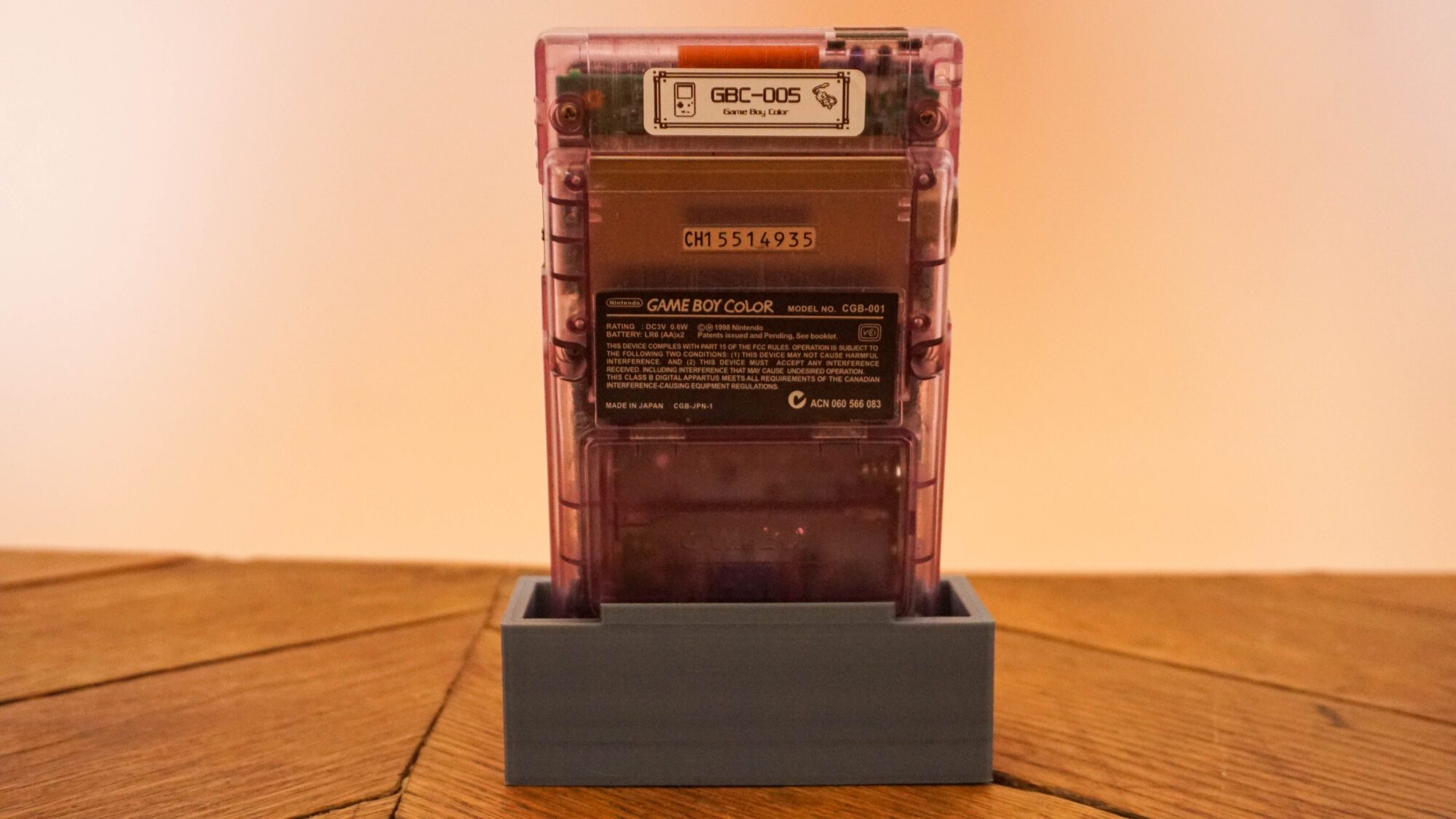 Photo d'une Game Boy Color Transparente/Violette sur son socle, vue de dos