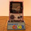 Photo d'une Game Boy Color Transparente/Violette sur son socle, vue de face
