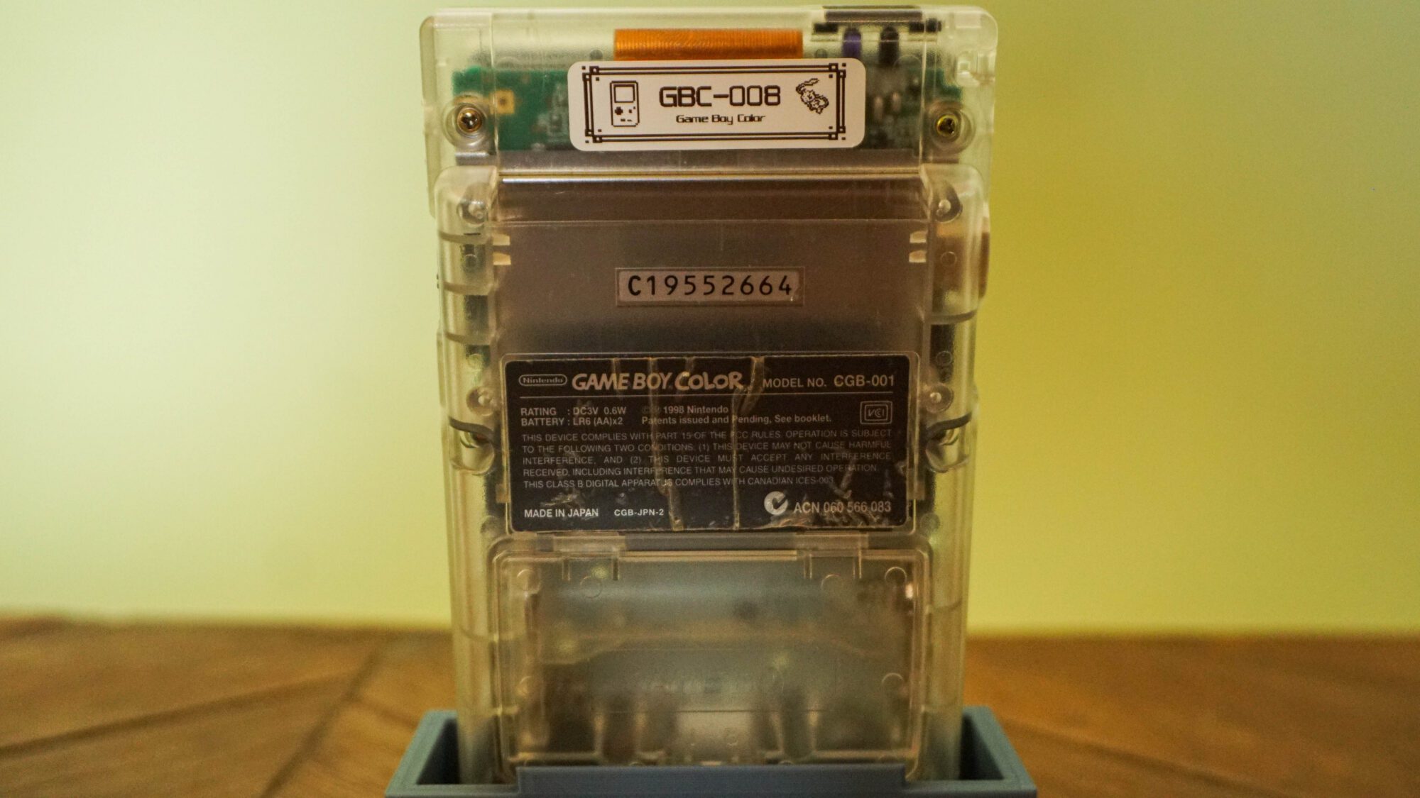 Photo d'une Game Boy Color Transparente sur son socle, vue de dos