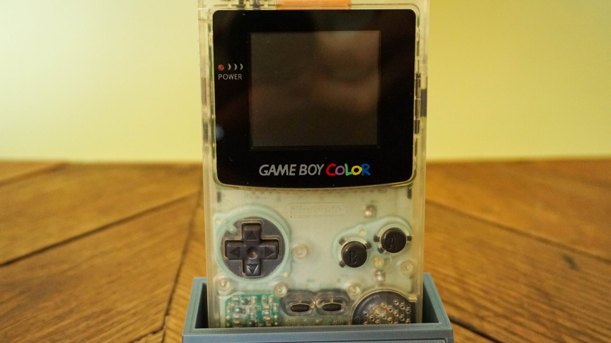 Photo d'une Game Boy Color Transparente sur son socle, vue de face