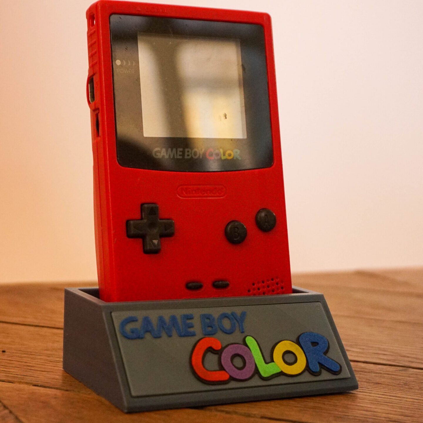Photo d'une Game Boy Color Rouge "Berry" sur son socle, vue de 3/4