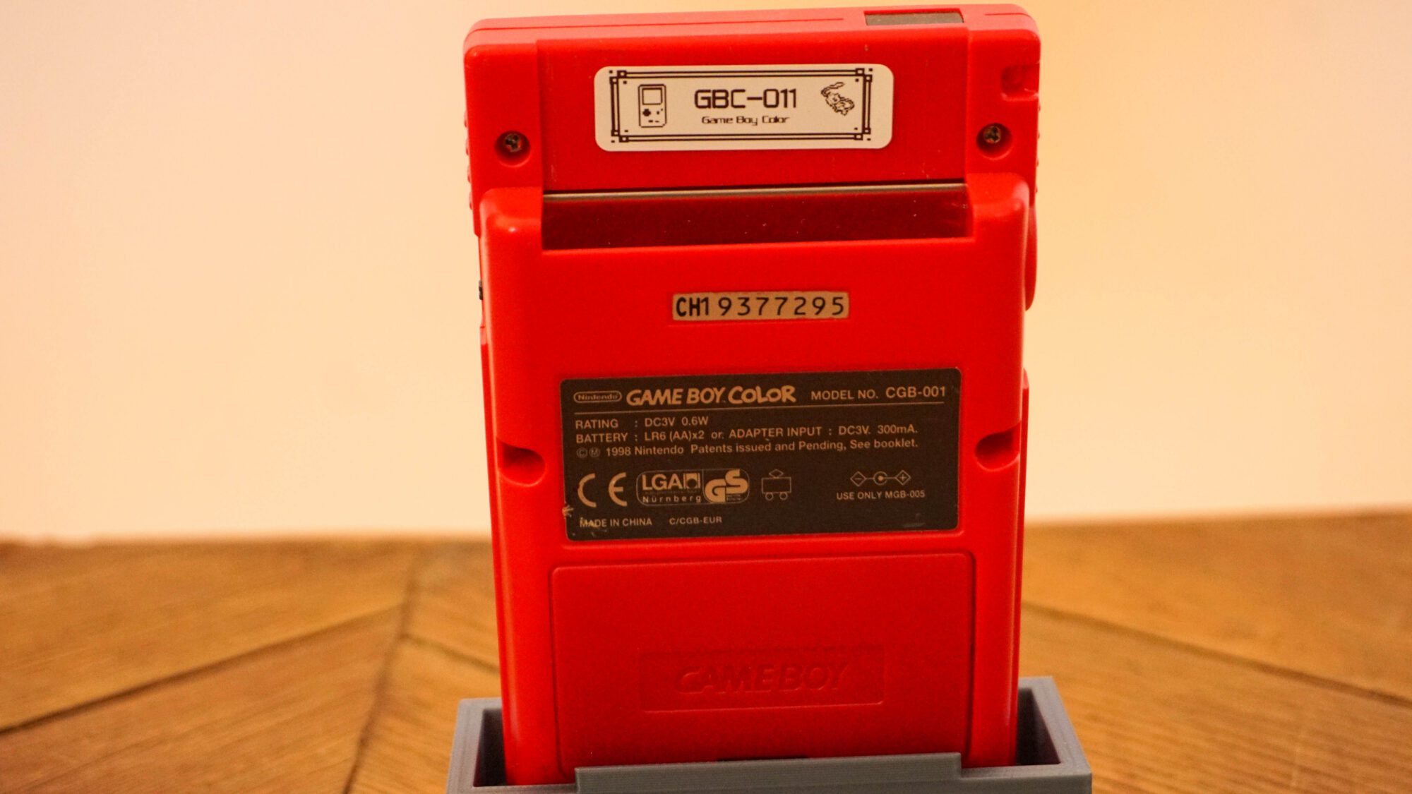 Photo d'une Game Boy Color Rouge "Berry" sur son socle, vue de dos