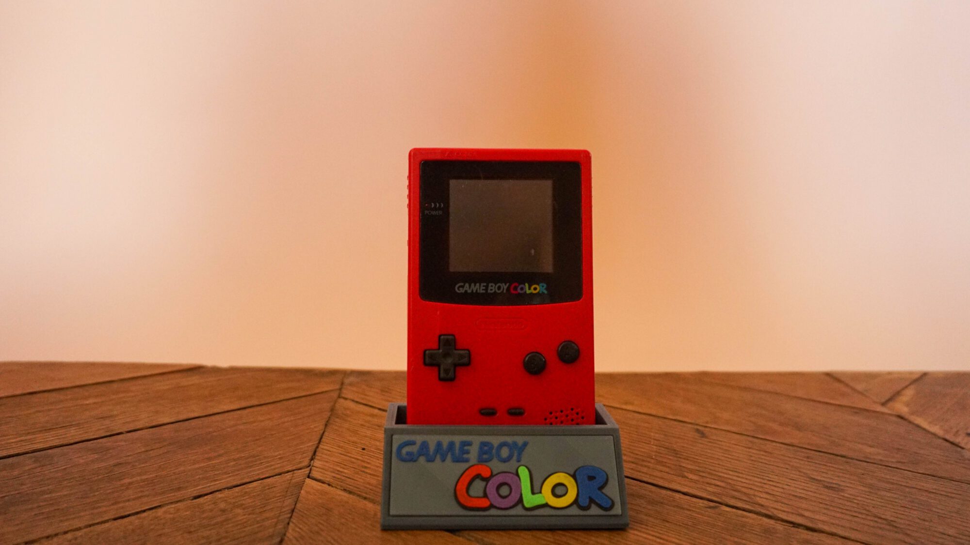 Photo d'une Game Boy Color Rouge "Berry" sur son socle, vue de face