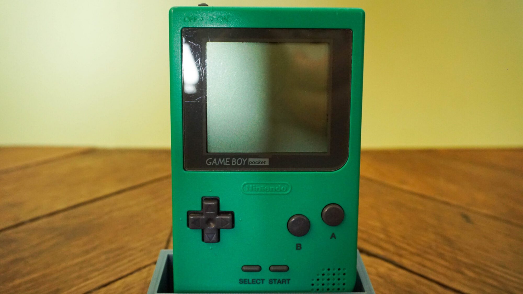 Photo d'une Game Boy Pocket Verte sur son socle, vue de face