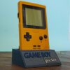Photo d'une Game Boy Pocket Jaune sur son socle, vue de 3/4