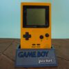 Photo d'une Game Boy Pocket Jaune sur son socle, vue de face