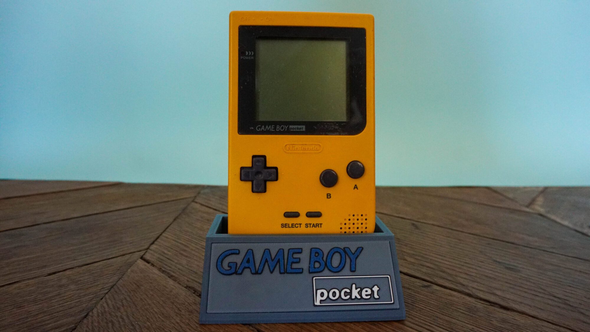Photo d'une Game Boy Pocket Jaune sur son socle, vue de face