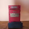 Photo d'une Game Boy Pocket Rose sur son socle, vue de dos