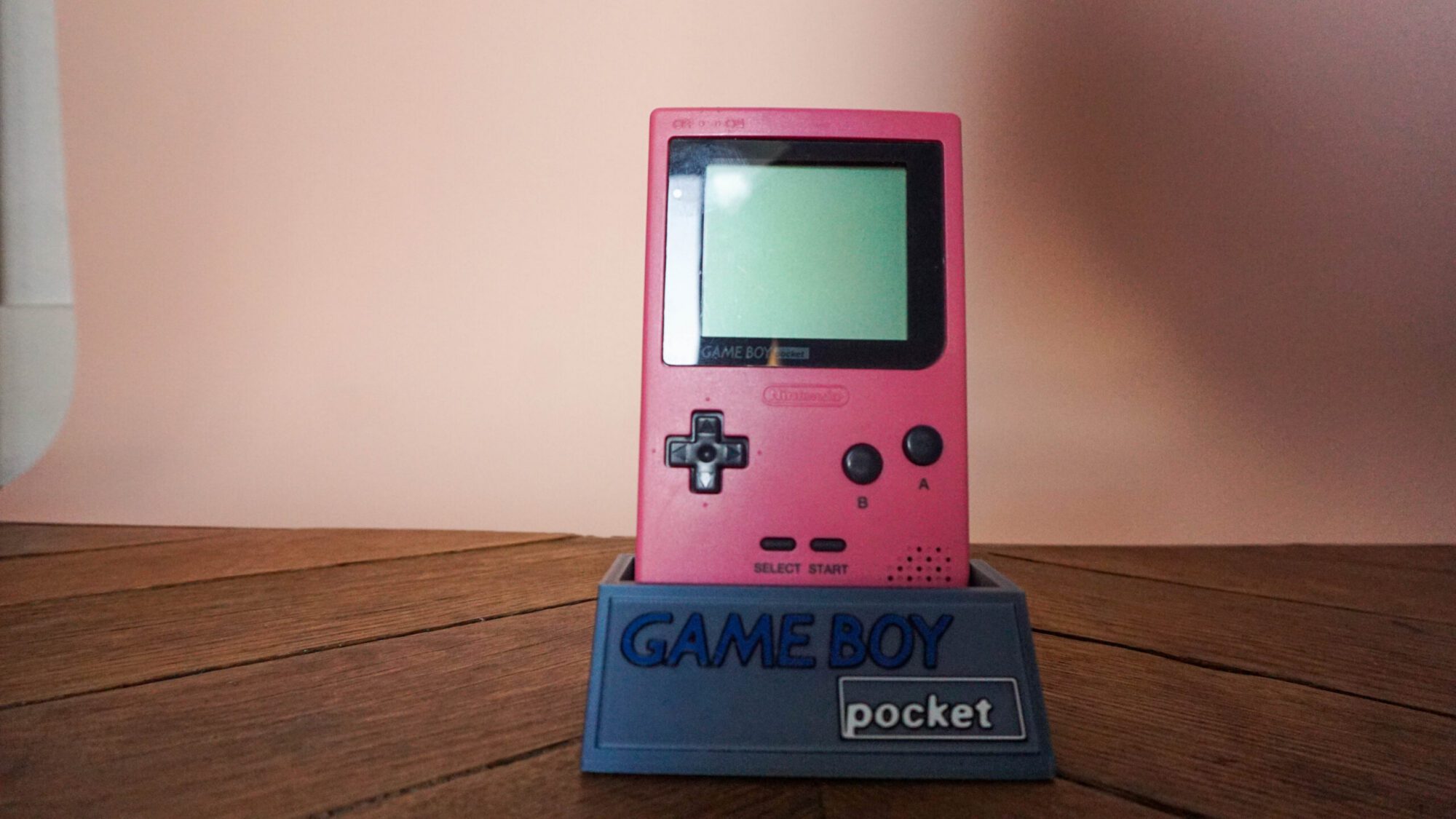 Photo d'une Game Boy Pocket Rose sur son socle, vue de face