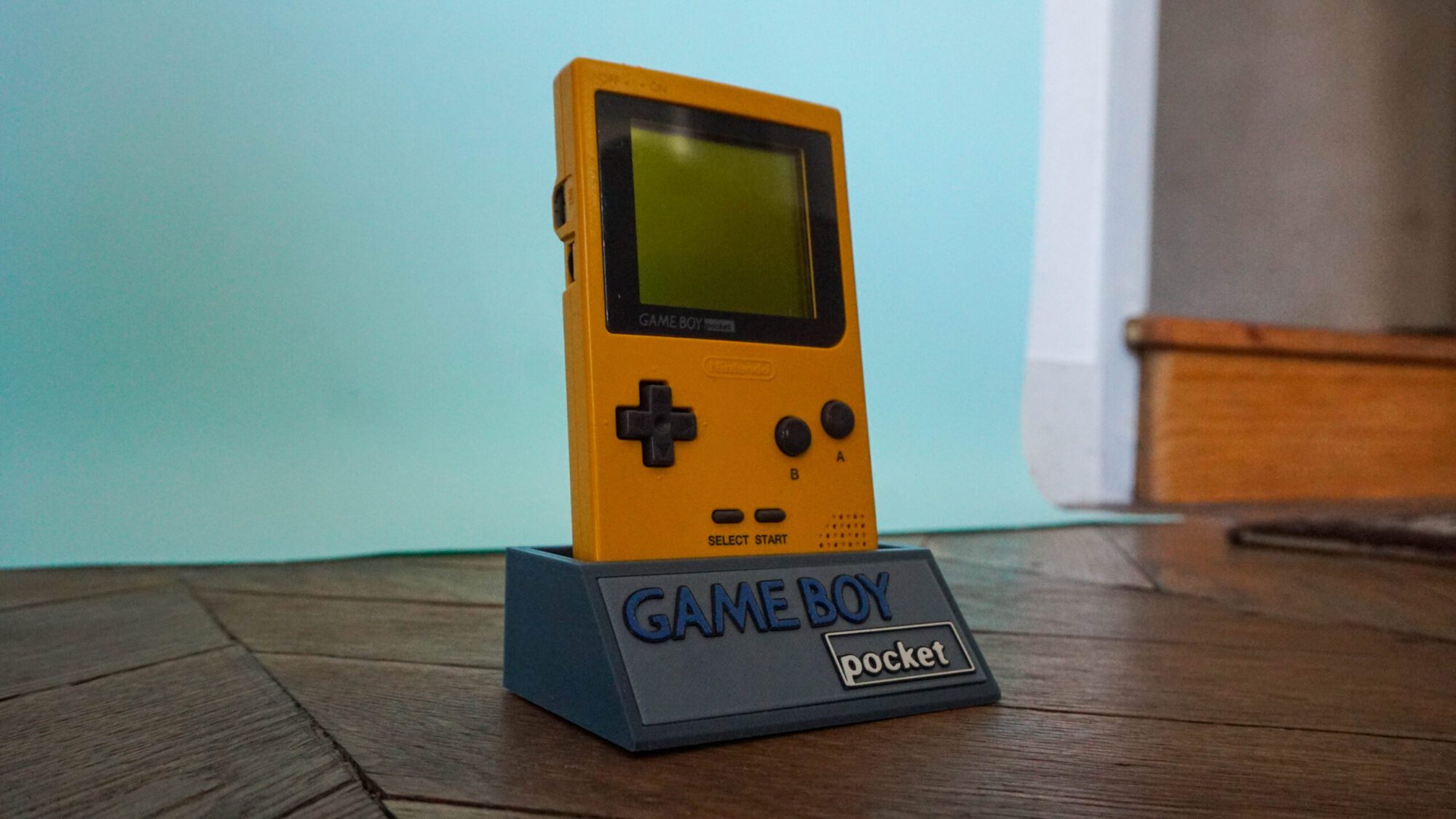 Photo d'une Game Boy Pocket Jaune sur son socle, vue de 3/4