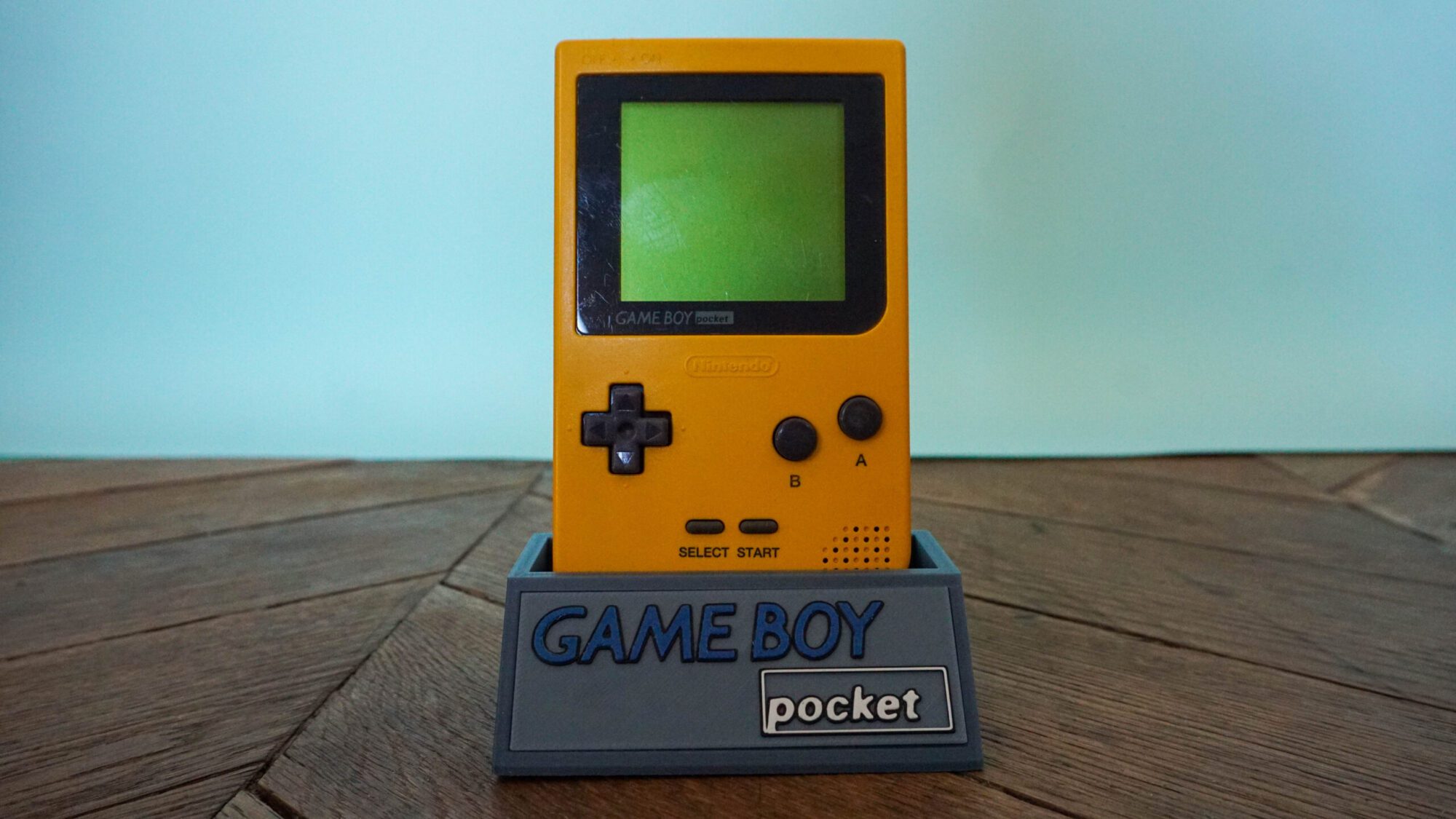 Photo d'une Game Boy Pocket Jaune sur son socle, vue de face