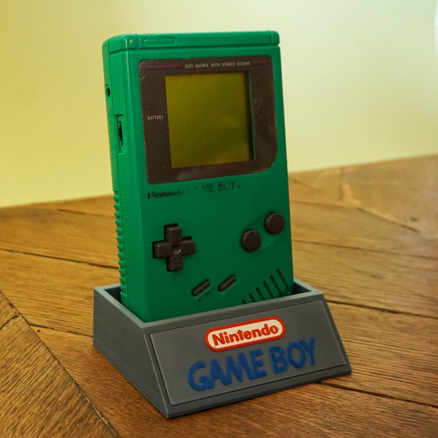 Photo d'une Game Boy Classic Verte restaurée sur son socle, vue de 3/4