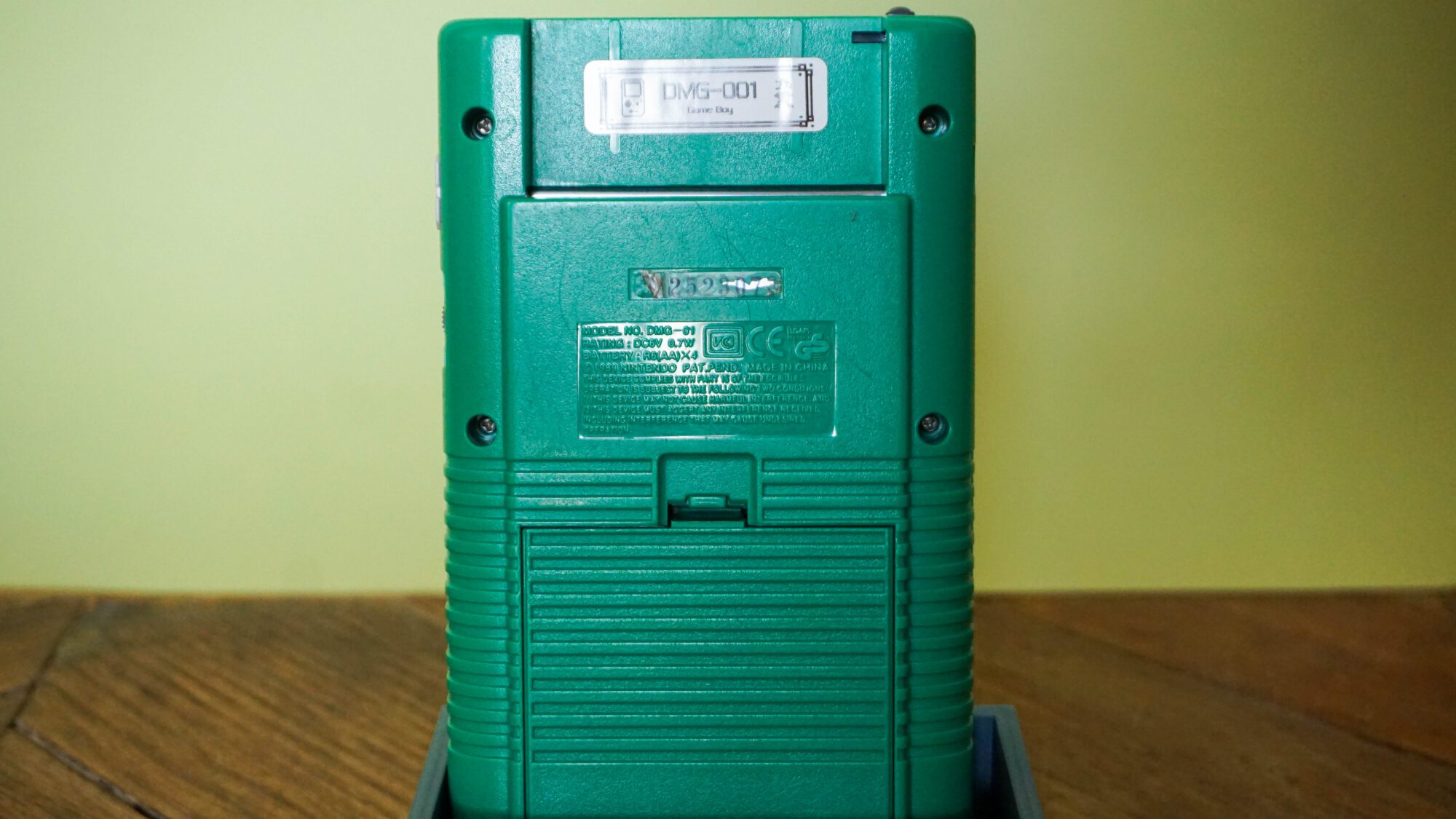 Photo d'une Game Boy Classic Verte sur son socle, vue de dos