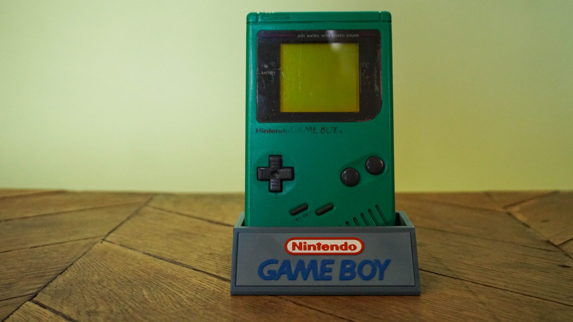 Photo d'une Game Boy Classic Verte sur son socle, vue de face