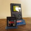 Photo d'une Game Boy Classic Noire sur son socle, vue de 3/4, avec le jeu Zelda Link's Awakening DX