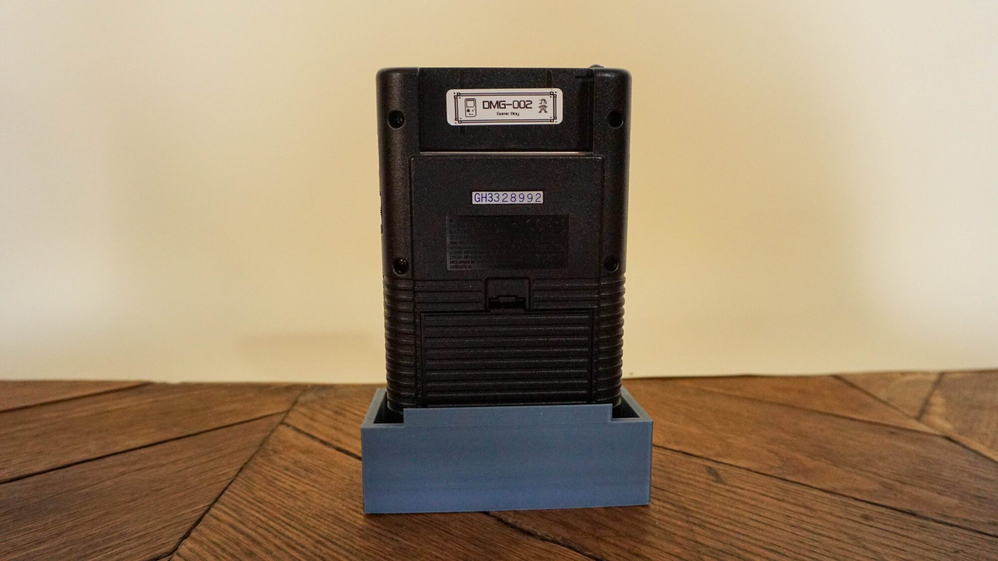 Photo d'une Game Boy Classic Noire sur son socle, vue de dos