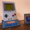 Photo d'une Game Boy Classic Grise sur son socle, vue de 3/4, avec le jeu Tetris