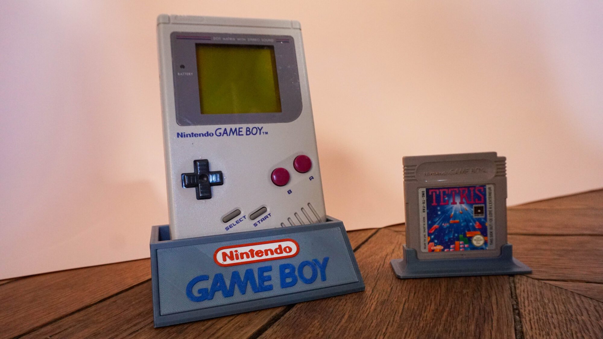 Photo d'une Game Boy Classic Grise sur son socle, vue de 3/4, avec le jeu Tetris