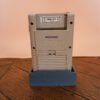 Photo d'une Game Boy Classic Grise sur son socle, vue de dos