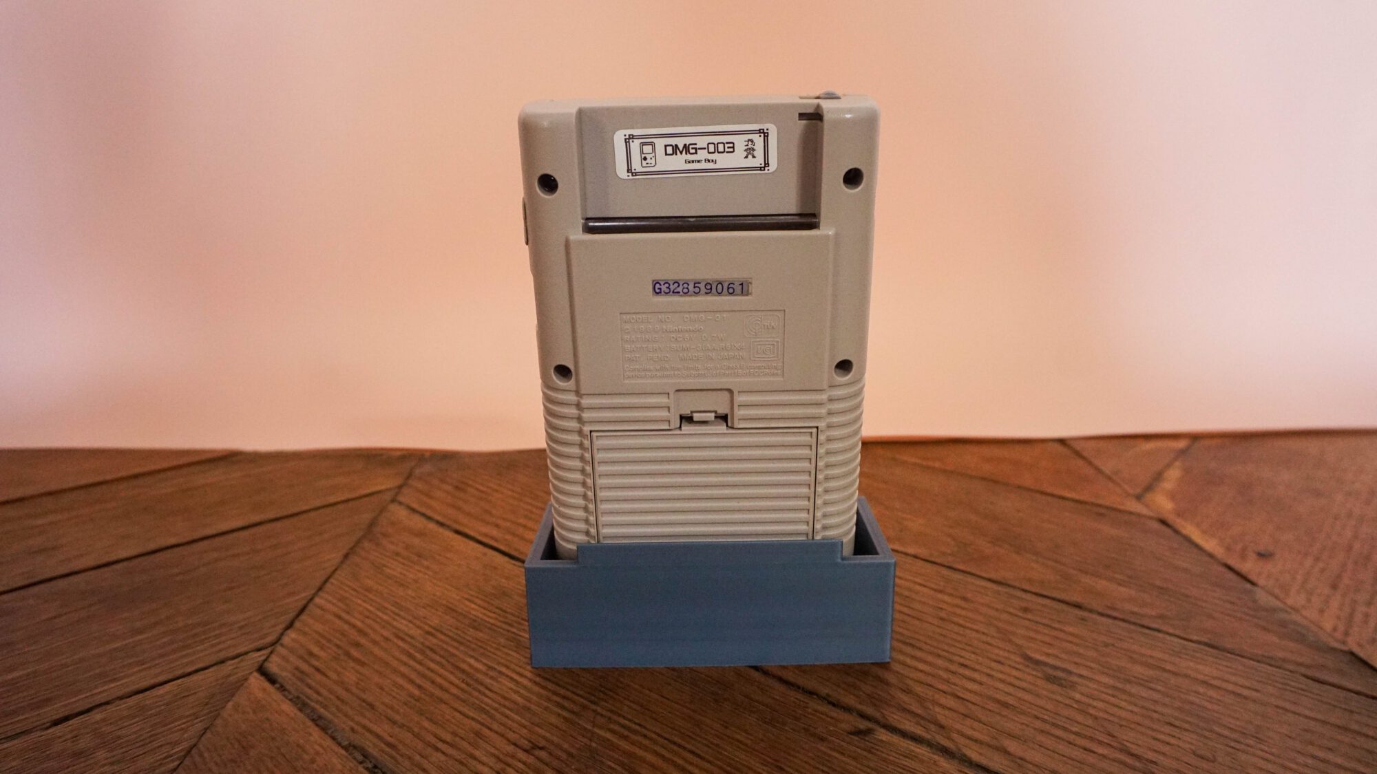 Photo d'une Game Boy Classic Grise sur son socle, vue de dos
