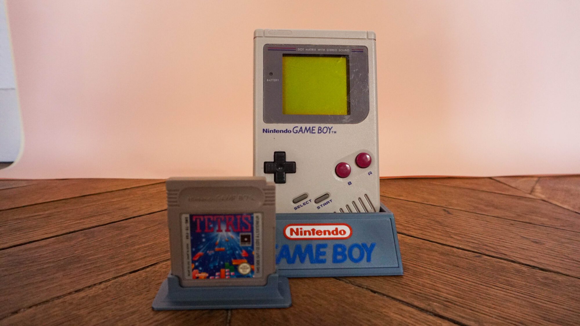 Photo d'une Game Boy Classic Grise sur son socle, vue de face, avec le jeu Tetris