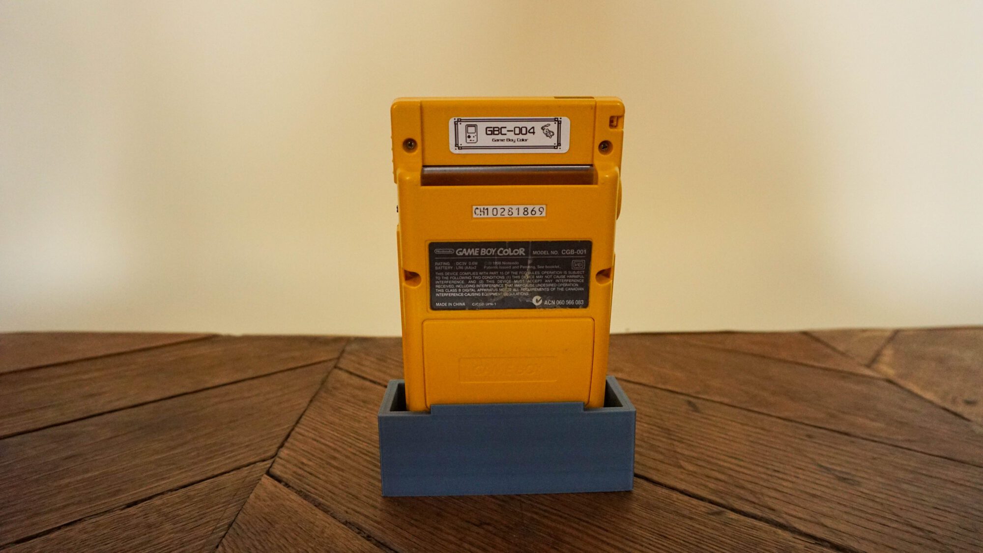 Photo d'une Game Boy Color Jaune sur son socle, vue de dos