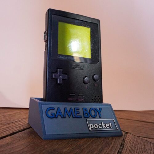 Photo d'une Game Boy Pocket Noire sur son socle, vue de 3/4