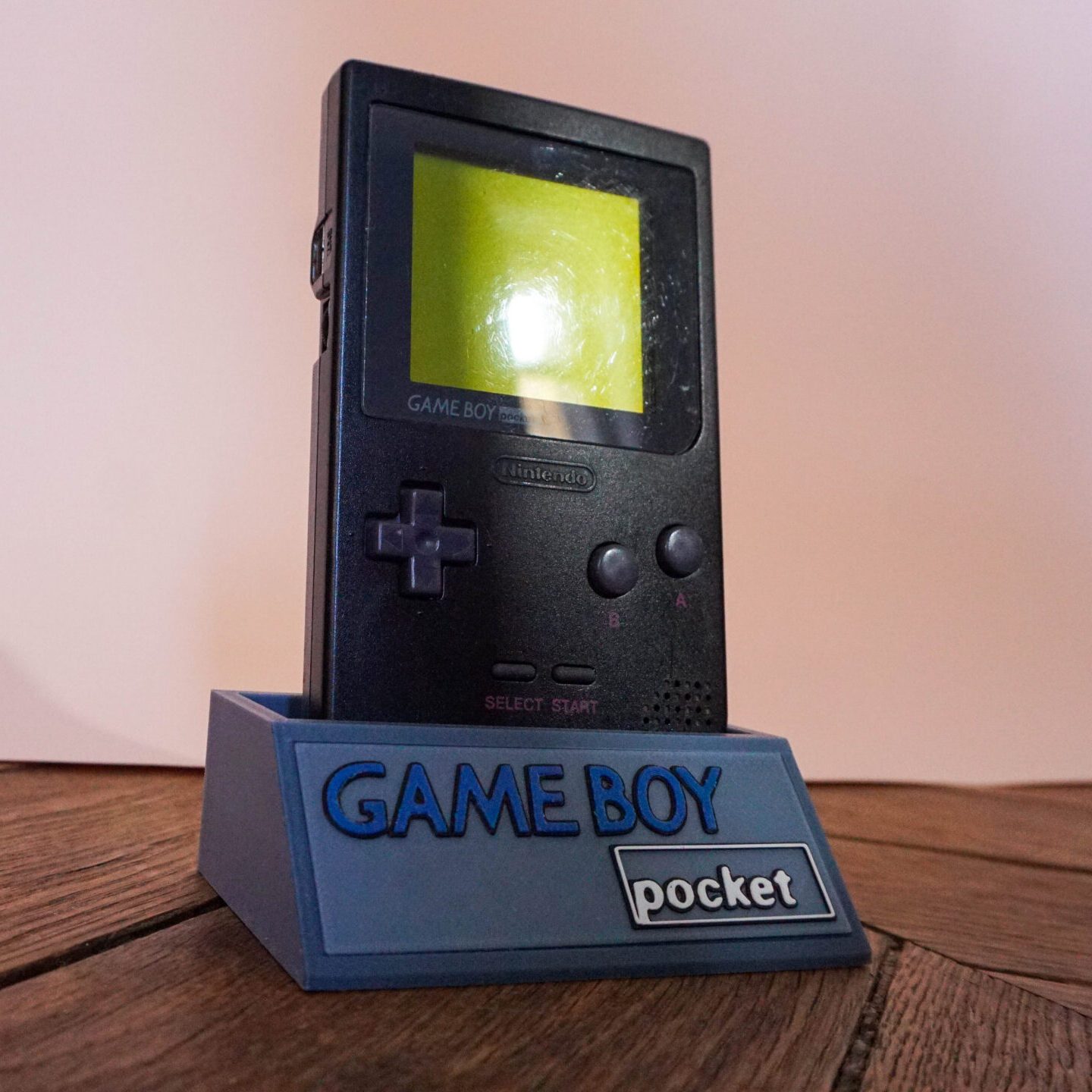 Photo d'une Game Boy Pocket Noire sur son socle, vue de 3/4