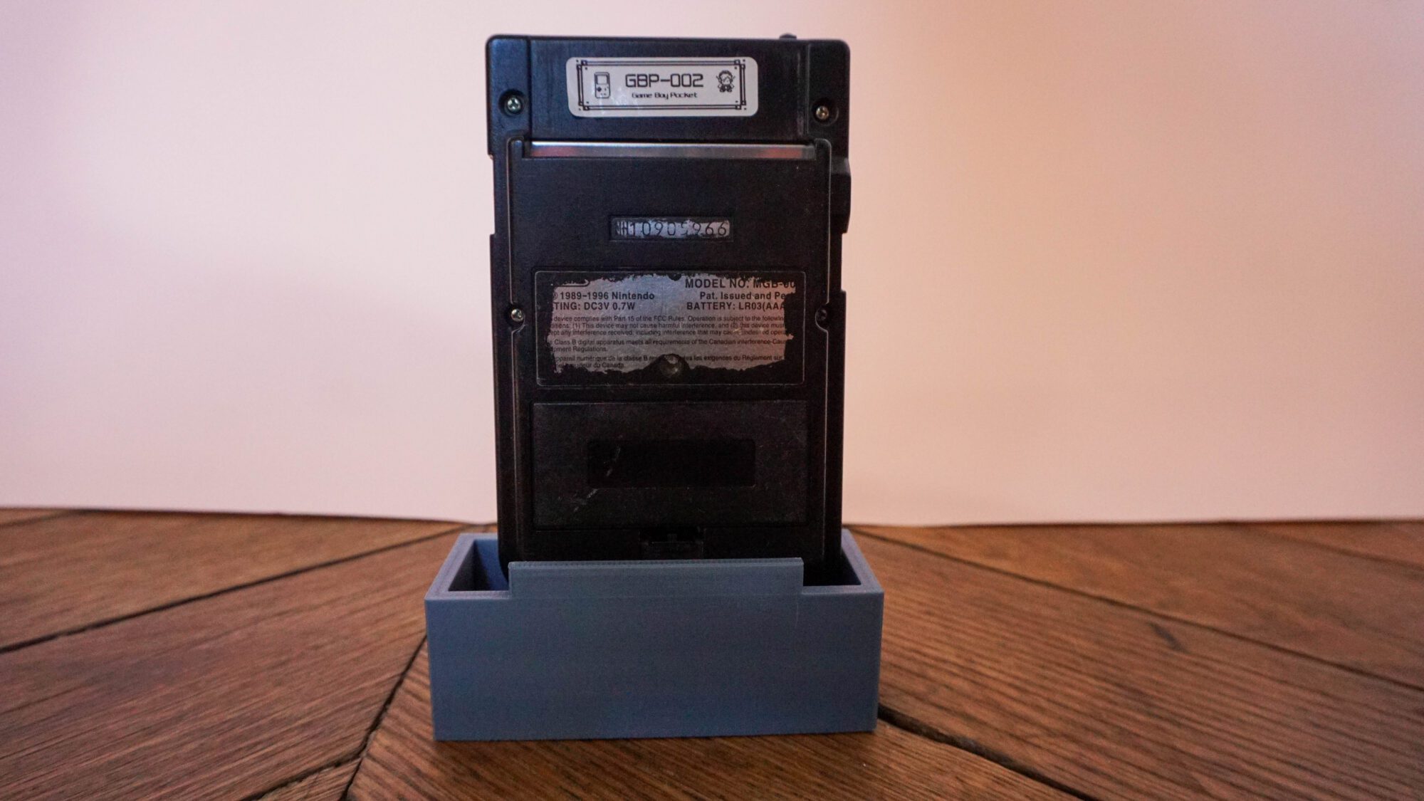Photo d'une Game Boy Pocket Noire sur son socle, vue de dos