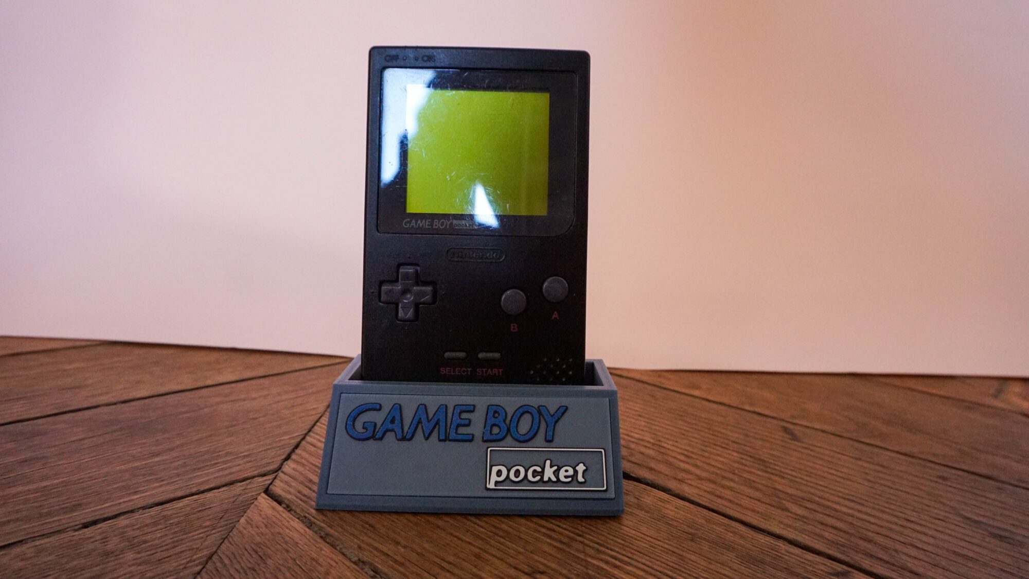 Photo d'une Game Boy Pocket Noire sur son socle, vue de face