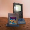 Photo d'une Game Boy Pocket Noire sur son socle, vue de 3/4, avec le jeu Super Mario Land