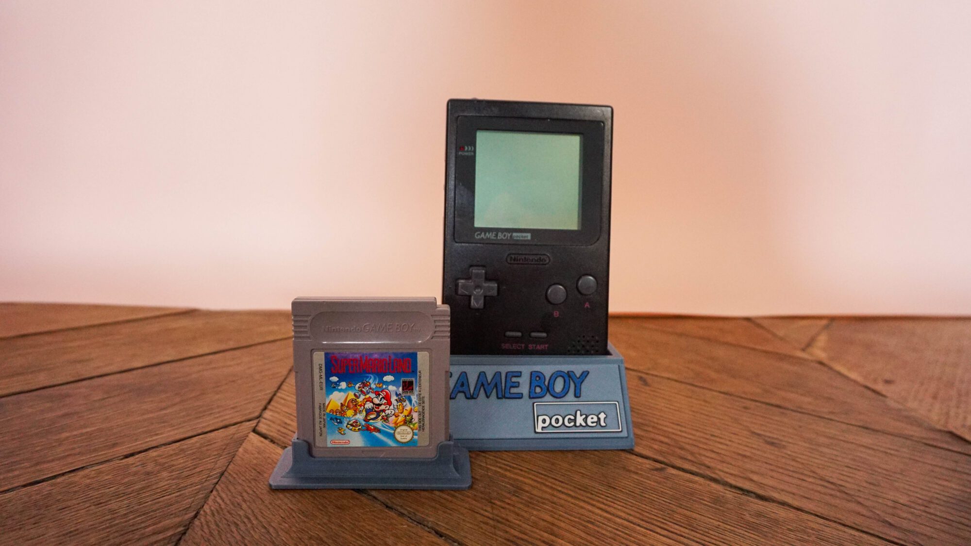Photo d'une Game Boy Pocket Noire sur son socle, vue de face, avec le jeu Super Mario Land