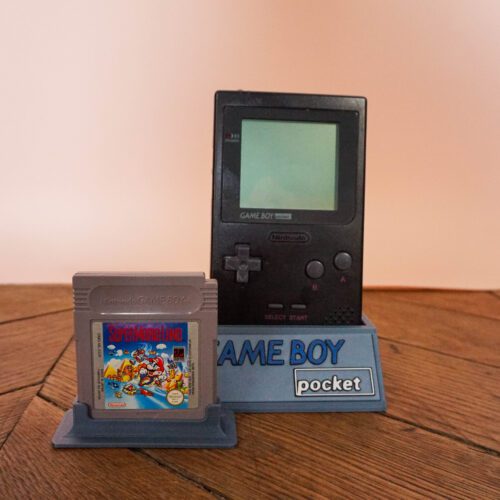 Photo d'une Game Boy Pocket Noire sur son socle, vue de face, avec le jeu Super Mario Land