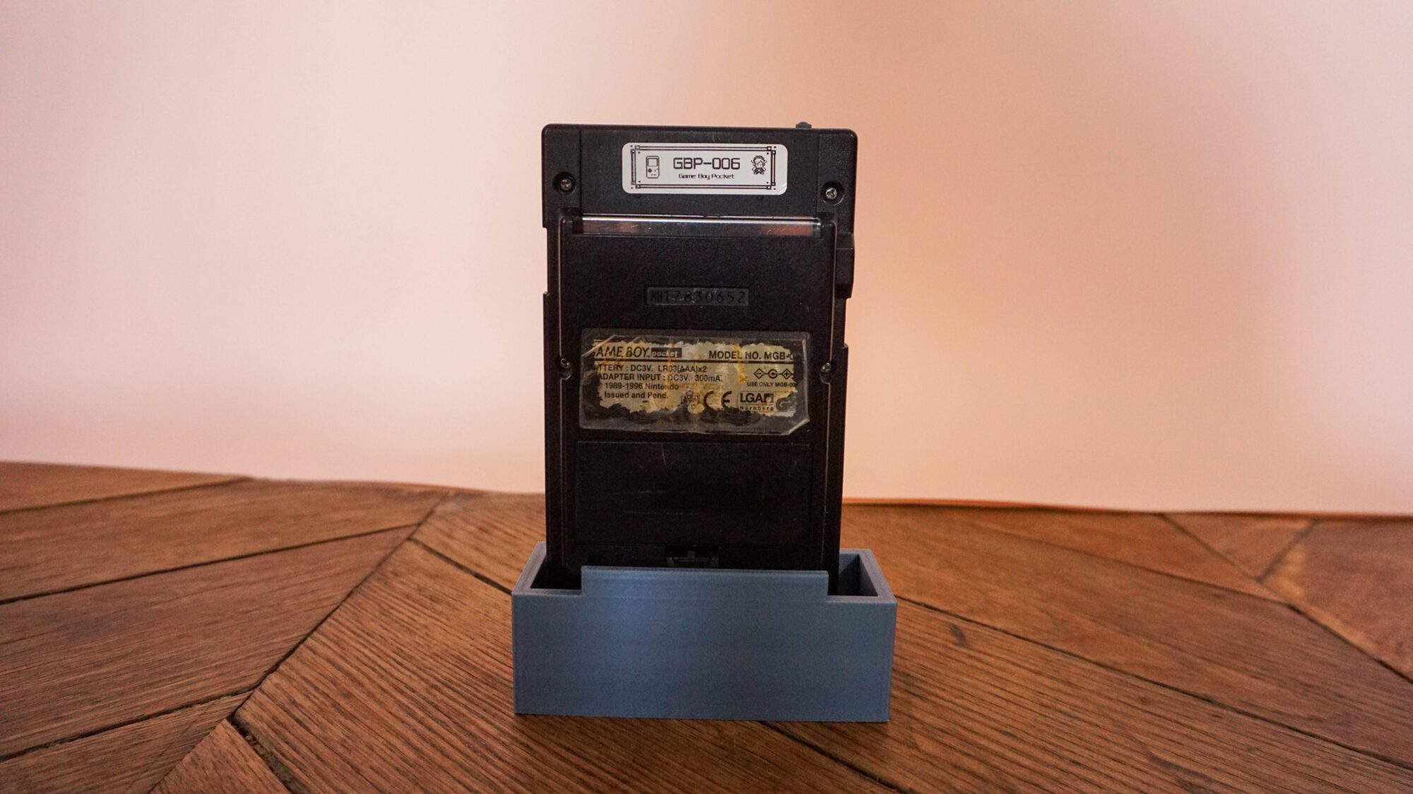 Photo d'une Game Boy Pocket Noire sur son socle, vue de dos